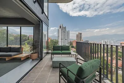 a balcony with green chairs and a view of a city at The Somos Loho Hotel in Medellín