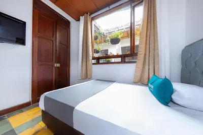 a bedroom with a large white bed with a window at Ayenda Sarayu House in Medellín