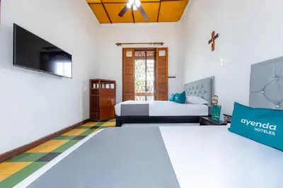 a bedroom with two beds and a flat screen tv at Ayenda Sarayu House in Medellín