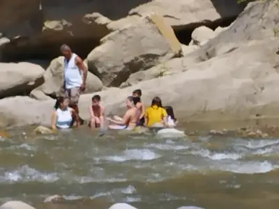 a group of people sitting in the water at hosteria y camping piedras verdes in Sopetran