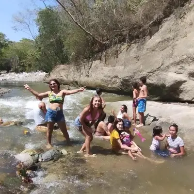 a group of people playing in the river at hosteria y camping piedras verdes in Sopetran
