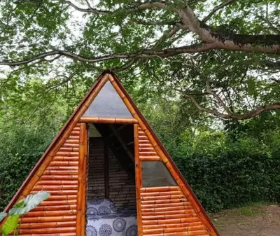 a small wooden cabin with a triangular roof under a tree at hosteria y camping piedras verdes in Sopetran