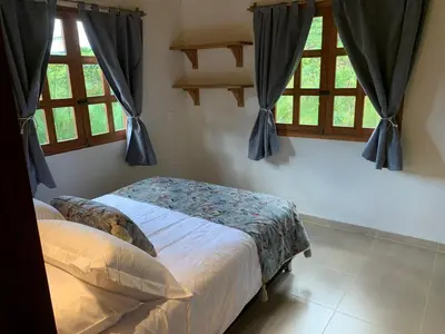 a bedroom with a bed and two windows at Casa Calandria - Vive Jardin in Jardin