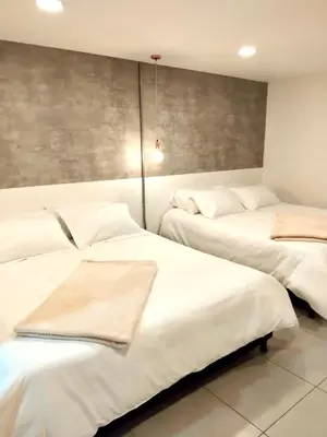 two beds in a room with white sheets at Urban Oasis Med in Medellín