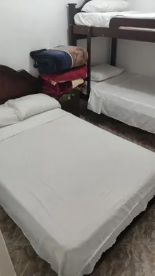 two beds in a room with white sheets at Hotel Los Colores GUATAPE in Guatapé