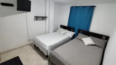 a bedroom with two beds and a blue curtain at Hotel Los Colores GUATAPE in Guatapé