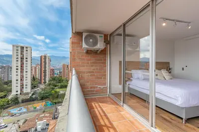 a bedroom with a bed and a balcony with a view at Torre Pravia By Host Medellin in Medellín