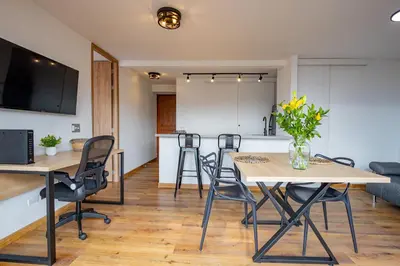 a living room with tables and chairs and a kitchen at Torre Pravia By Host Medellin in Medellín