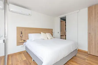 a white bedroom with a large bed with white sheets at Torre Pravia By Host Medellin in Medellín