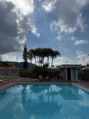 a large blue swimming pool with a cloudy sky at Hotel Campestre Alto lindo en Guatapé in Guatapé