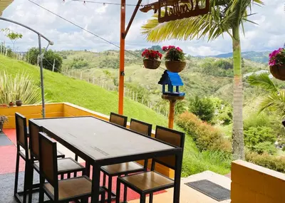 a table and chairs on a porch with a view at Hotel Campestre Alto lindo en Guatapé in Guatapé