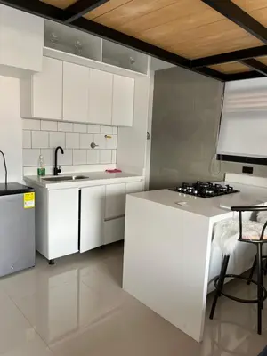 a kitchen with white cabinets and a sink and a table at Suite ps8 in Medellín