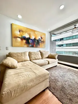 a living room with a couch and a painting on the wall at Hermoso apartamento en El Poblado in Medellín