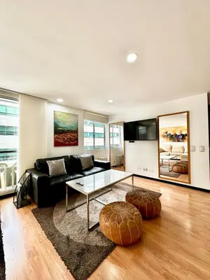 a living room with a black couch and a table at Hermoso apartamento en El Poblado in Medellín