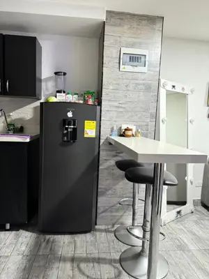 a kitchen with a black refrigerator and a table at Apartamento alto de palmas in Medellín