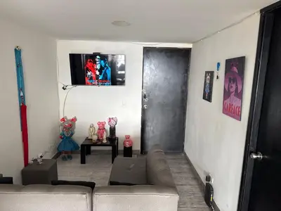 a living room with a couch and a tv on the wall at Apartamento alto de palmas in Medellín