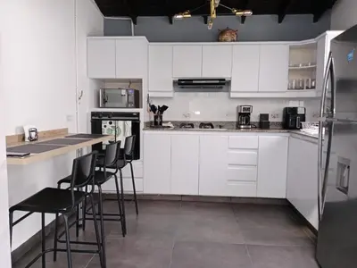 a kitchen with white cabinets and bar stools at Envigado tradicion y modernidad in Envigado
