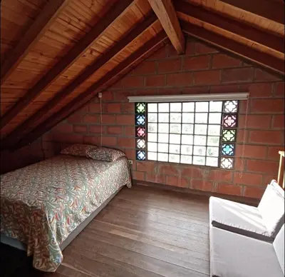 a attic room with a bed and a window at Finca Oriente Antioqueño Guarne Rionegro in Guarne