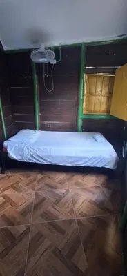 a small bed in a room with a wooden floor at Cabaña Los Almendros in Puerto Triunfo
