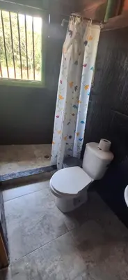 a bathroom with a toilet and a shower curtain at Cabaña Los Almendros in Puerto Triunfo