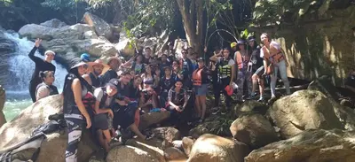 a group of people sitting on rocks near a river at Cabaña Los Almendros in Puerto Triunfo