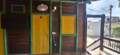 a house with yellow and green doors and a balcony at Cabaña Los Almendros in Puerto Triunfo