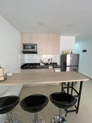 a kitchen with a wooden counter with four stools at Acogedor y cómodo apartamento in Sabaneta