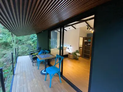 a room with a table and chairs on a deck at Luxury Cabin in the Forest in El Retiro
