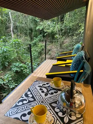 a table with two cups and a tea pot on a deck at Luxury Cabin in the Forest in El Retiro