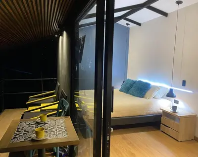 a bedroom with a bed and a table with chairs at Luxury Cabin in the Forest in El Retiro