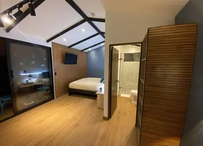 a room with a bathroom with a bed and a toilet at Luxury Cabin in the Forest in El Retiro