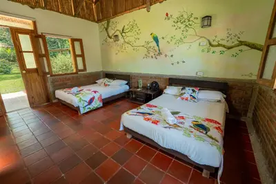a bedroom with two beds and a painting on the wall at Tinamú Birding and Nature Lodge in Manizales