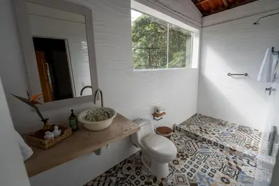 a bathroom with a toilet and a sink and a mirror at Tinamú Birding and Nature Lodge in Manizales