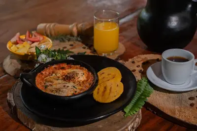 a table with a bowl of food and a glass of orange juice at Tinamú Birding and Nature Lodge in Manizales