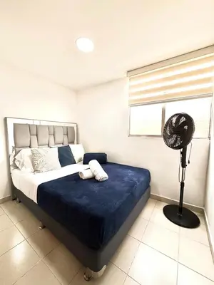 a bedroom with a bed with a blue blanket and a fan at Alojamiento Central en Medellín en Zona Turística BA in Medellín