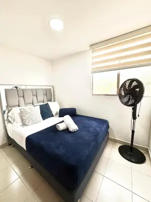 a bedroom with a bed with a blue blanket and a fan at Alojamiento Central en Medellín en Zona Turística BA in Medellín