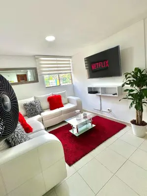 a living room with a white couch and a red rug at Alojamiento Central en Medellín en Zona Turística BA in Medellín