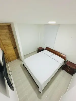 a small bedroom with a white bed and a tv at La camelia in Jardin