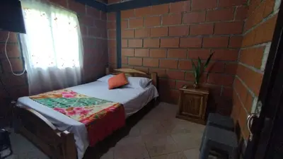 a small bedroom with a bed and a brick wall at Cabaña Mirador Santa Ana in San Rafael