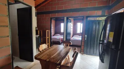 a room with a wooden table and a bedroom at Cabaña Mirador Santa Ana in San Rafael