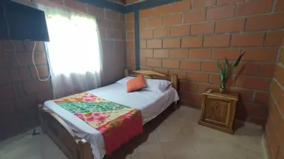 a small bedroom with a bed and a brick wall at Cabaña Mirador Santa Ana in San Rafael