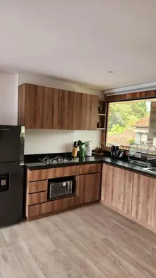 a kitchen with wooden cabinets and a black refrigerator at New Countryside Apartaloft 213 in El Retiro