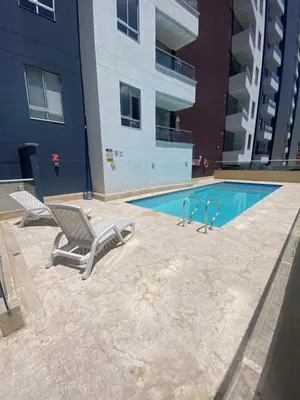 a swimming pool with two lounge chairs next to a building at Lujoso y acogedor apartamento in Sabaneta