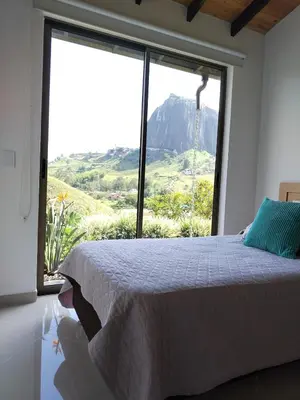 a bedroom with a bed and a large window at Increíble villa de lujo, vistas espectaculares in Guatapé