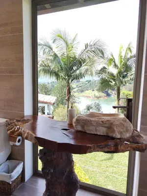 a wooden table in front of a window with palm trees at Increíble villa de lujo, vistas espectaculares in Guatapé