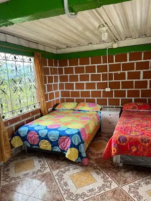 a room with two beds and a brick wall at Andean Mot Mot Coffee - Puerto Asís Farm in Aranzazu