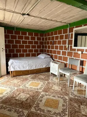 a bedroom with a brick wall with a bed and two chairs at Andean Mot Mot Coffee - Puerto Asís Farm in Aranzazu