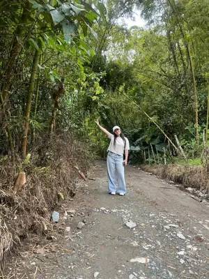 a man walking down a dirt road with his arm in the air at Andean Mot Mot Coffee - Puerto Asís Farm in Aranzazu