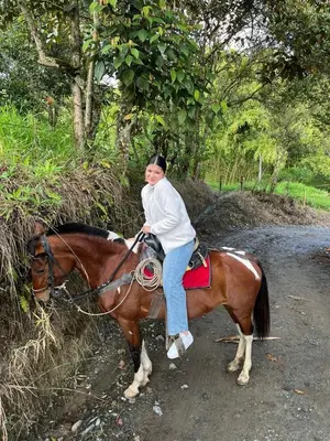 a woman riding a horse on a dirt road at Andean Mot Mot Coffee - Puerto Asís Farm in Aranzazu