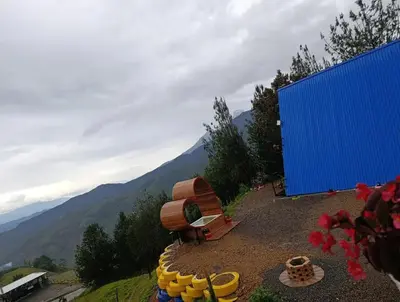 a blue building with a bunch of yellow barrels on a hill at Glamping Arcoiris in Ciudad Bolívar